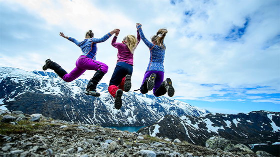 three female hikers jumping in mountain landscape