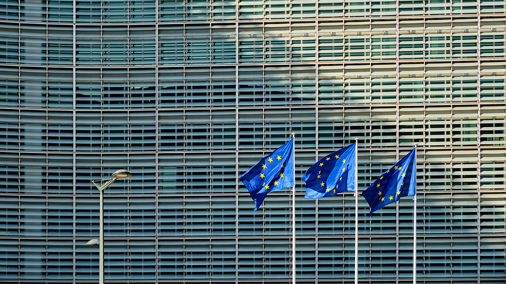 Tre EU-flagg foran stor kontorbygning